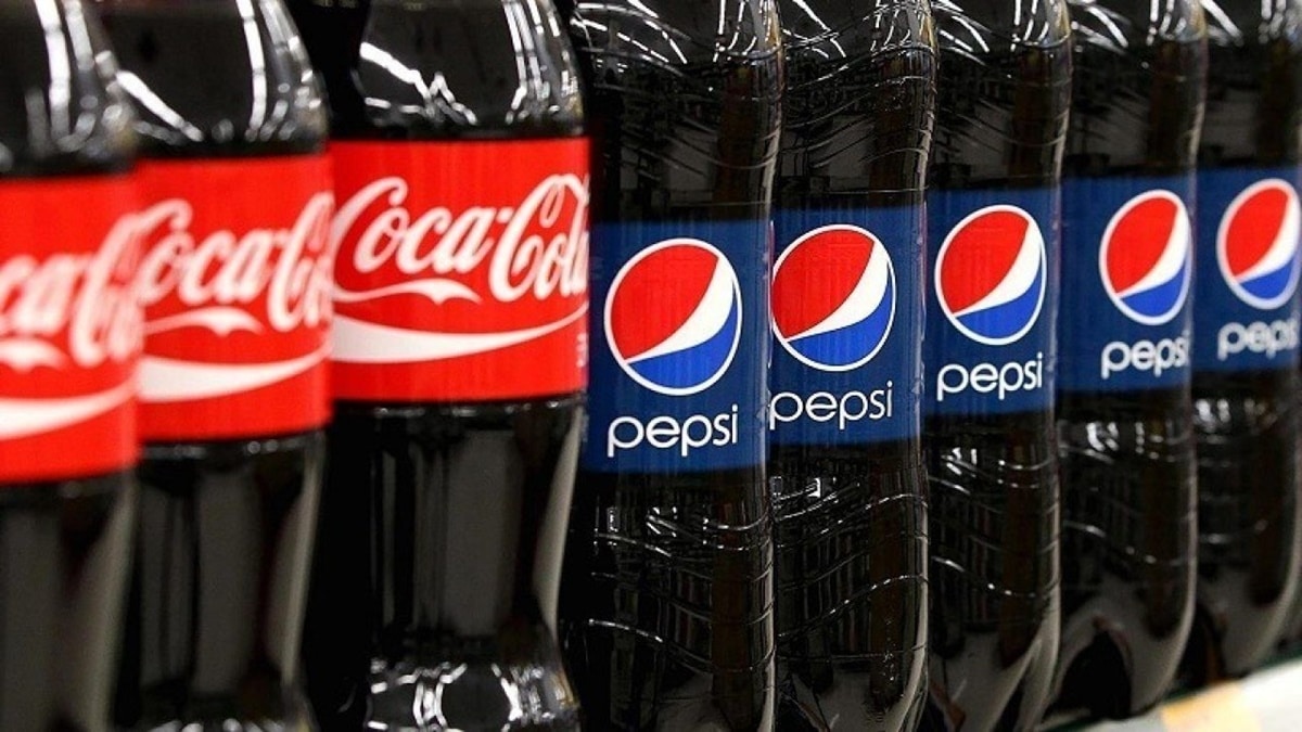 Garrafas de Coca-Cola e Pepsi lado a lado nas prateleiras 