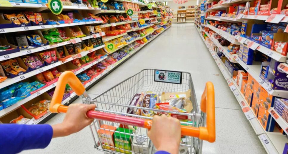 Cliente com carrinho de supermercado em corredor fazendo suas compras