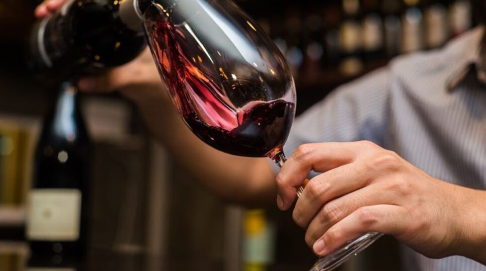 Pessoa colocando vinho tinto em uma taça