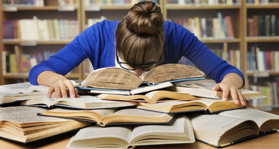 Estudante debruçada em cima de montanha de livros (Foto: Reprodução/ Internet)