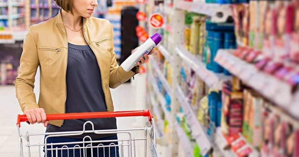 Cliente em gôndolas de supermercado com produto de beleza nas mãos (Foto: Reprodução/ Istock.com/ Getty images)