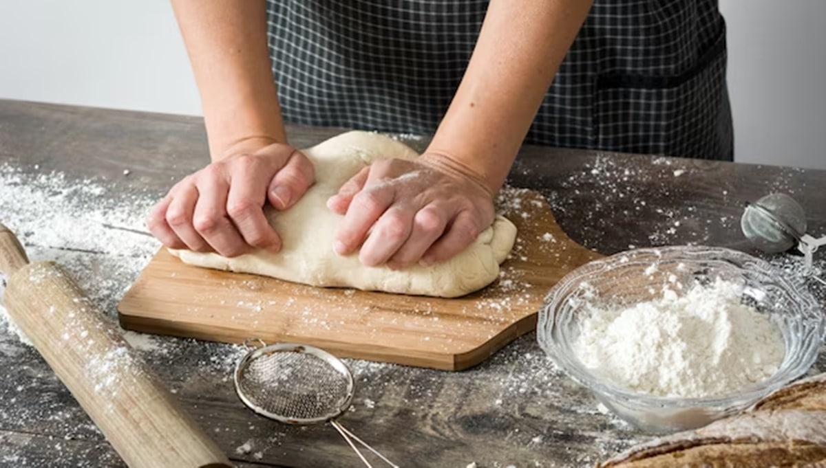 Massa de pão sendo sivada rapidamente por cozinheira (Foto: Reprodução/ GettyImages)