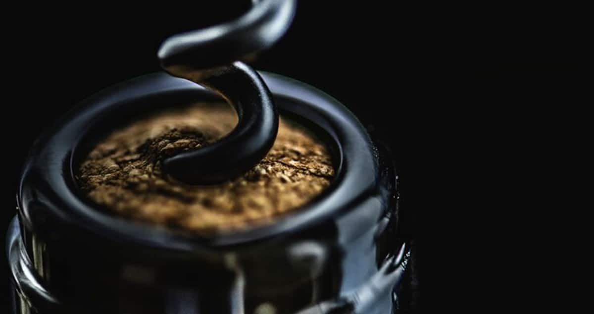 Garrafa de vinho sendo aberta com retirada da rolha de cortiça (Foto: Reprodução/ FreePik)